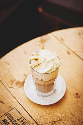 Iced coffee with whipped cream and banana slices on wooden table