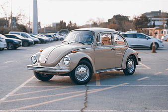 Classic beige Volkswagen Beetle parked in a modern urban parking lot