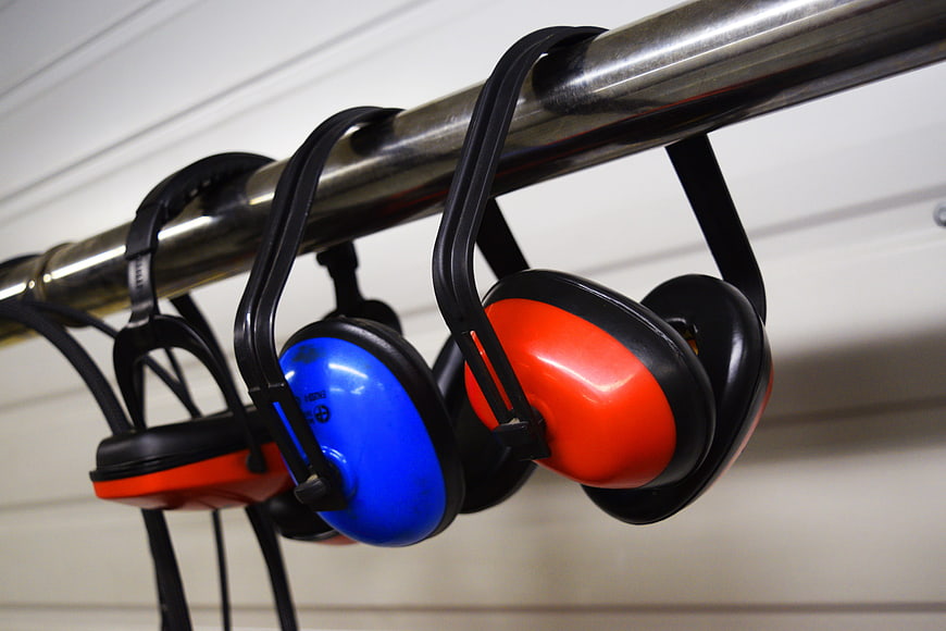Colorful Safety Earmuffs Hanging on Metal Bar