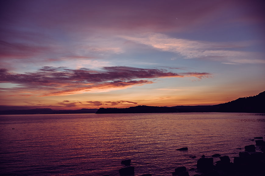 Dramatic purple and orange sunset over calm ocean water