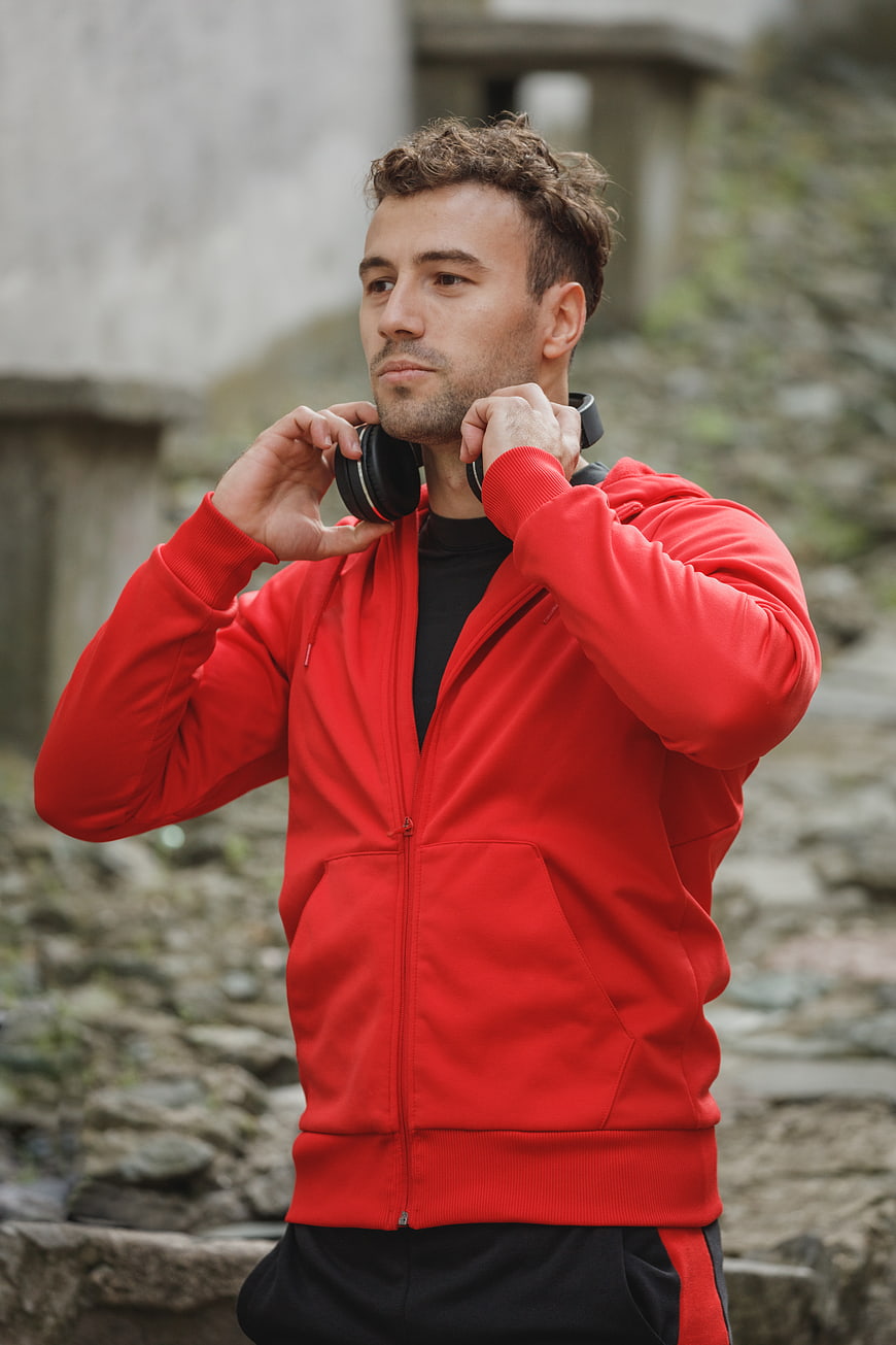 Man in Red Hoodie Putting on Headphones Outdoors