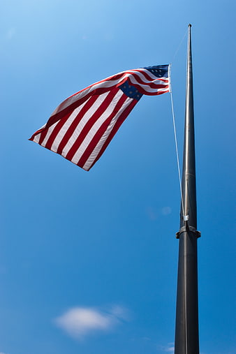 American Flag at Half-Mast Against Blue Sky