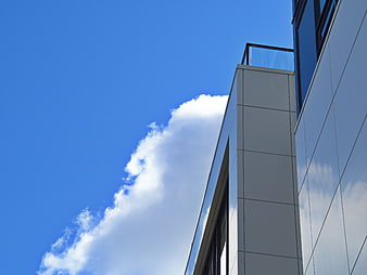Modern building facade against blue sky with clouds