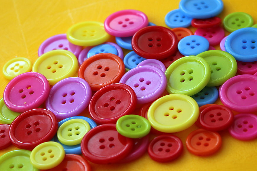 Colorful Plastic Sewing Buttons on Yellow Background