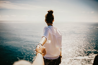 Couple holding hands walking towards ocean view