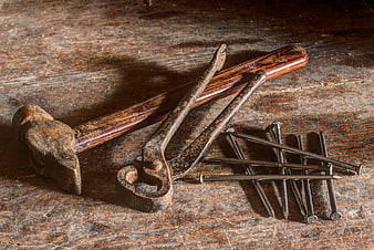 Vintage rusty hammer, pliers, and nails on old wood