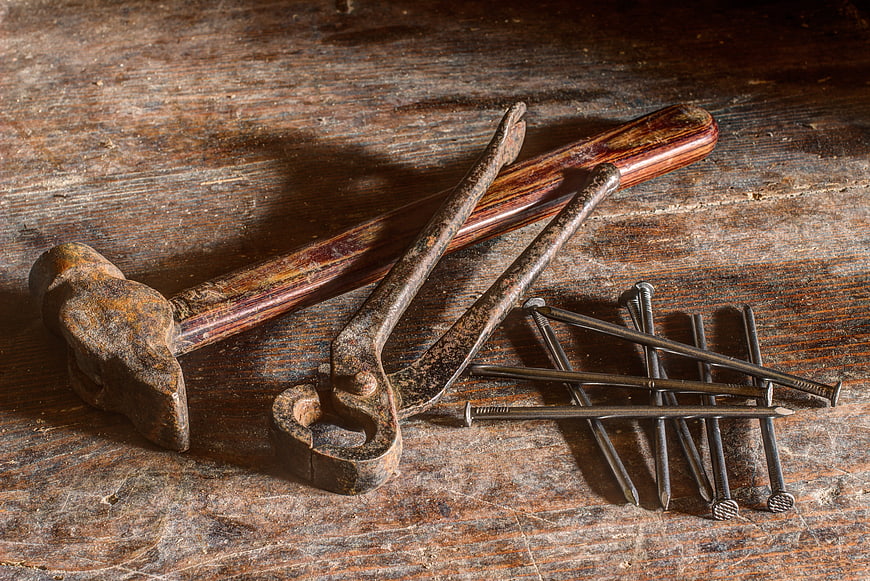 Vintage rusty hammer, pliers, and nails on old wood