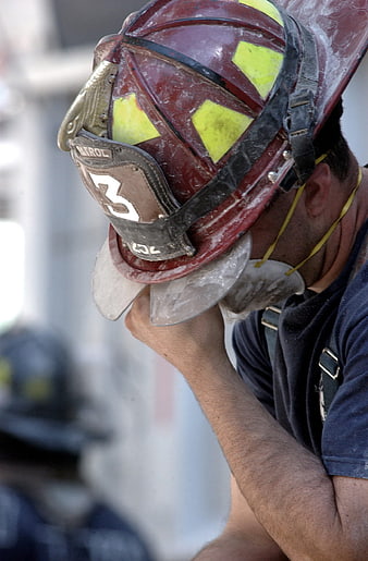 Close-up of a weary firefighter wearing a dusty red helmet with number 3