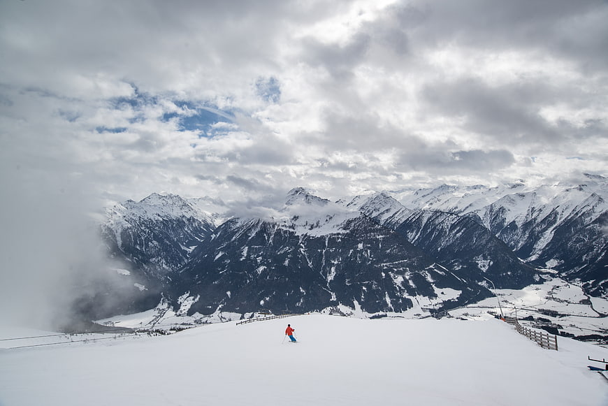 Lone skier on snowy mountain slope with dramatic clouds