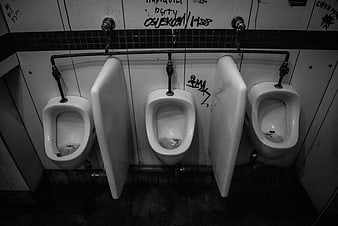 Black and white photo of three urinals in a public restroom