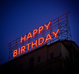 Red Neon Happy Birthday Sign on Building Roof at Night