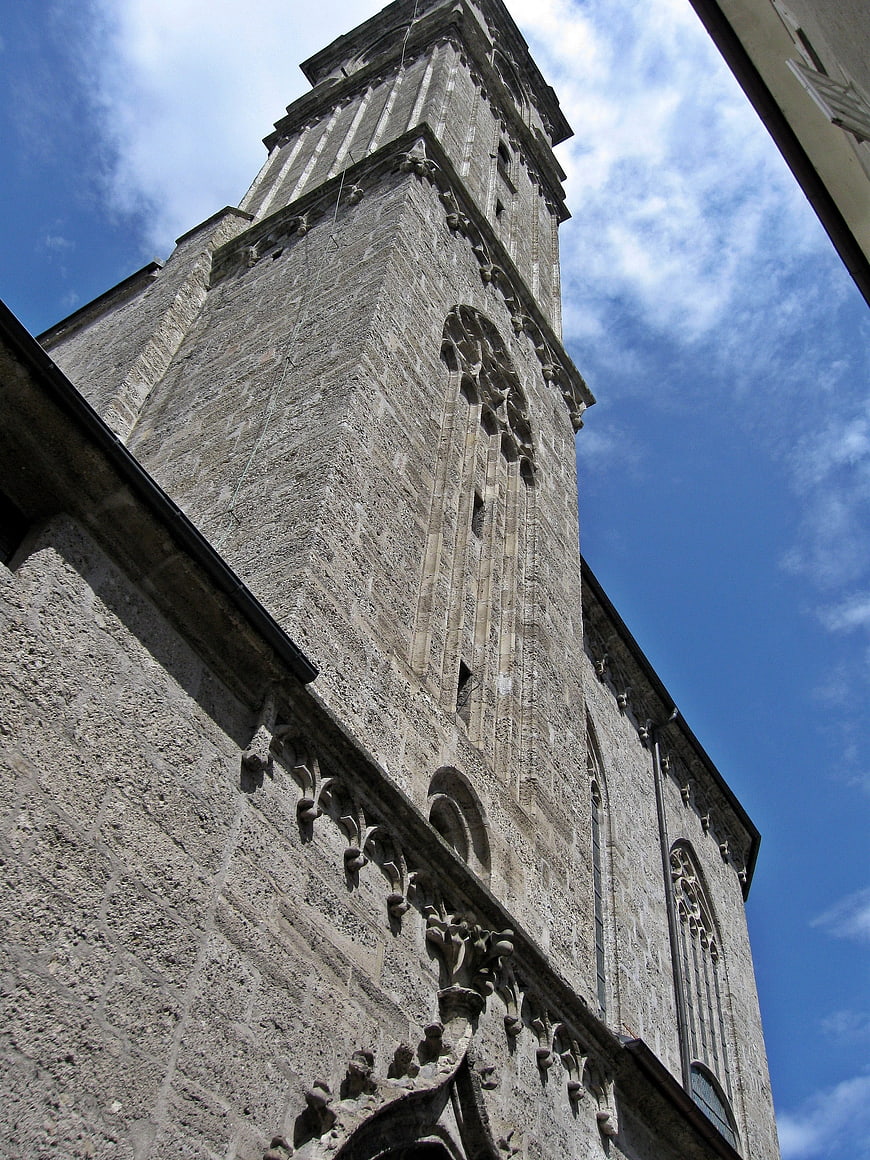 Low angle view of historic stone church tower against blue sky