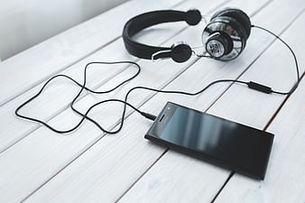 Black Smartphone and Headphones on White Wooden Table