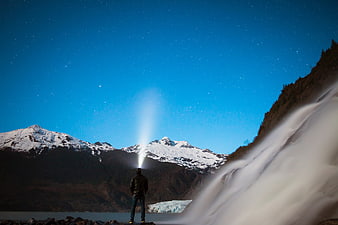 Man with Flashlight Beam Under Starry Night Sky