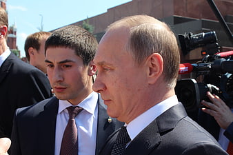 Vladimir Putin in profile with security and press cameras