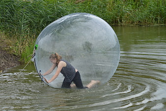 Woman inside transparent zorb ball in river water
