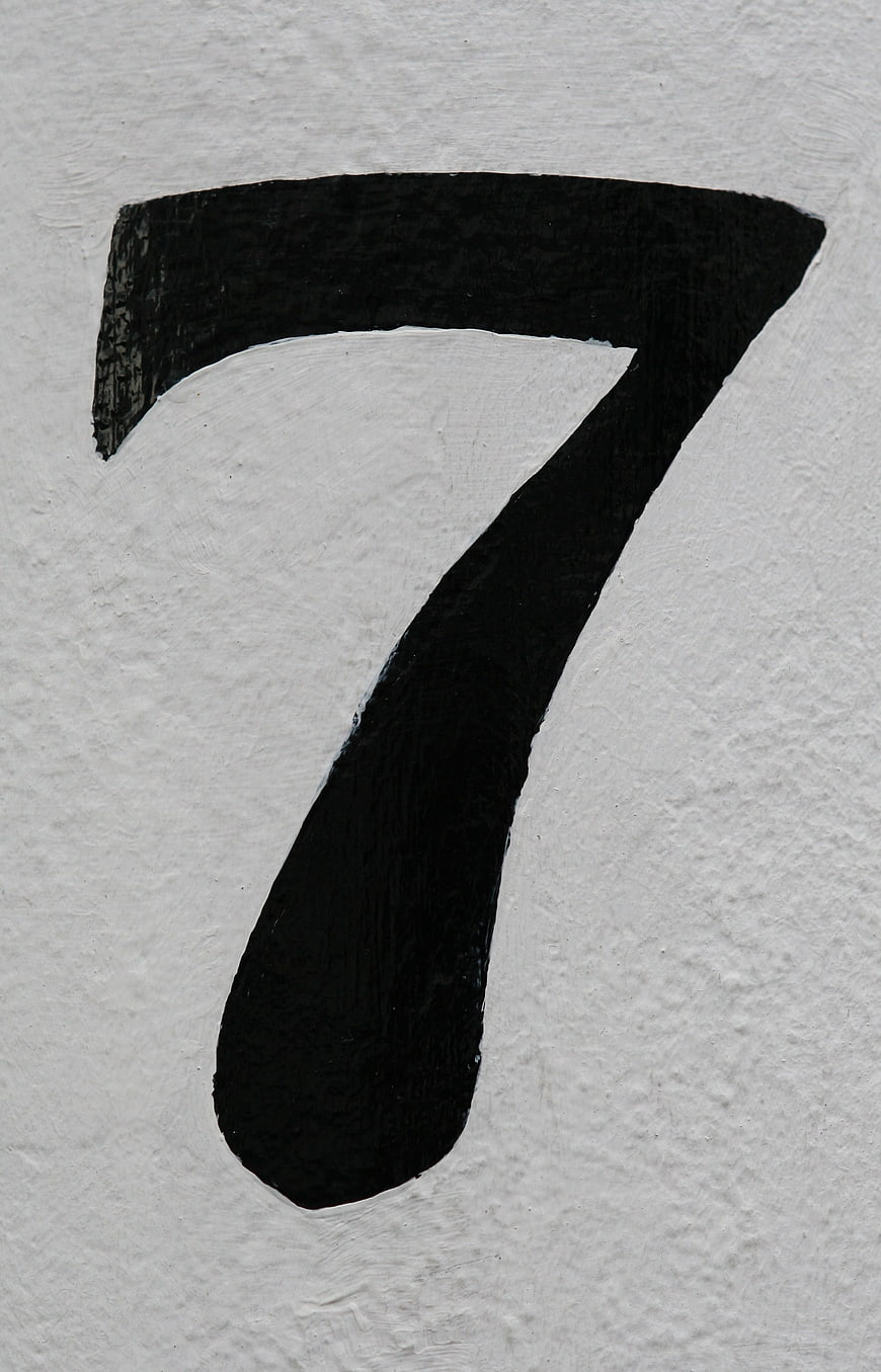Hand-painted black number seven on textured white paper background