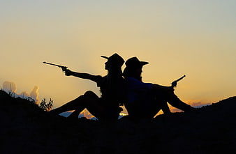 Silhouette of two cowboys with revolvers at sunset