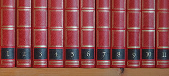 Row of red leather-bound books numbered 1 to 11 on a wooden shelf