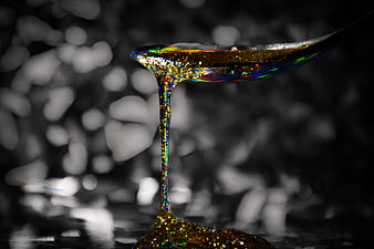 Golden Glitter Honey Dripping from Spoon on Dark Background