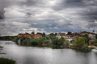 Riverside village with houses under dramatic cloudy sky