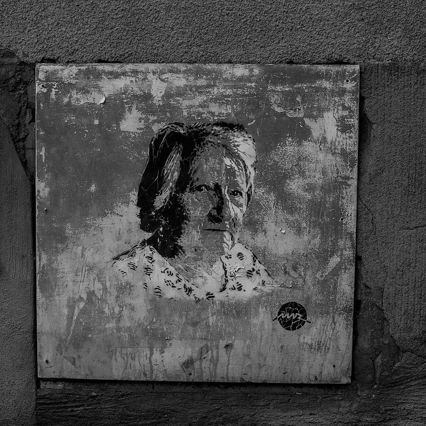Black and white street art portrait of elderly woman on wall
