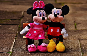 Mickey and Minnie Mouse plush toys sitting on a bench