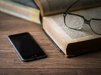 Smartphone and Open Book with Glasses on Wooden Table