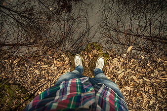 First-person view of person standing on mossy rock by water