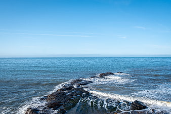Rocky Coastline with Crashing Waves and Blue Sky