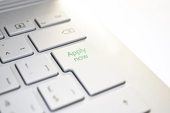 Close-up of white laptop keyboard with green apply now text