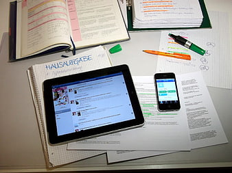 Student desk with tablet, smartphone, and homework notes