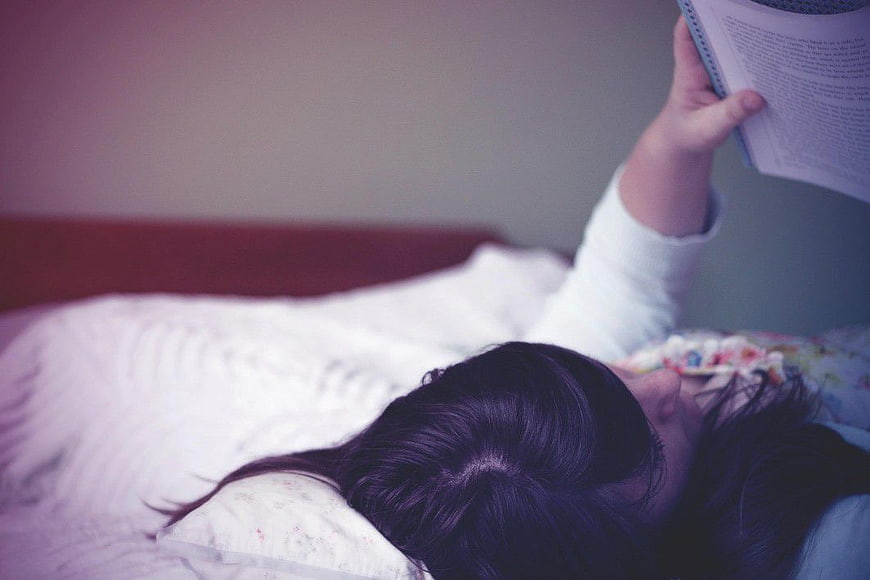 Woman Reading Book in Bed Overhead View