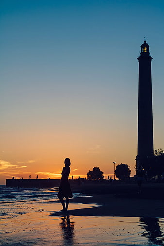 Woman Silhouette on Beach at Sunset with Lighthouse
