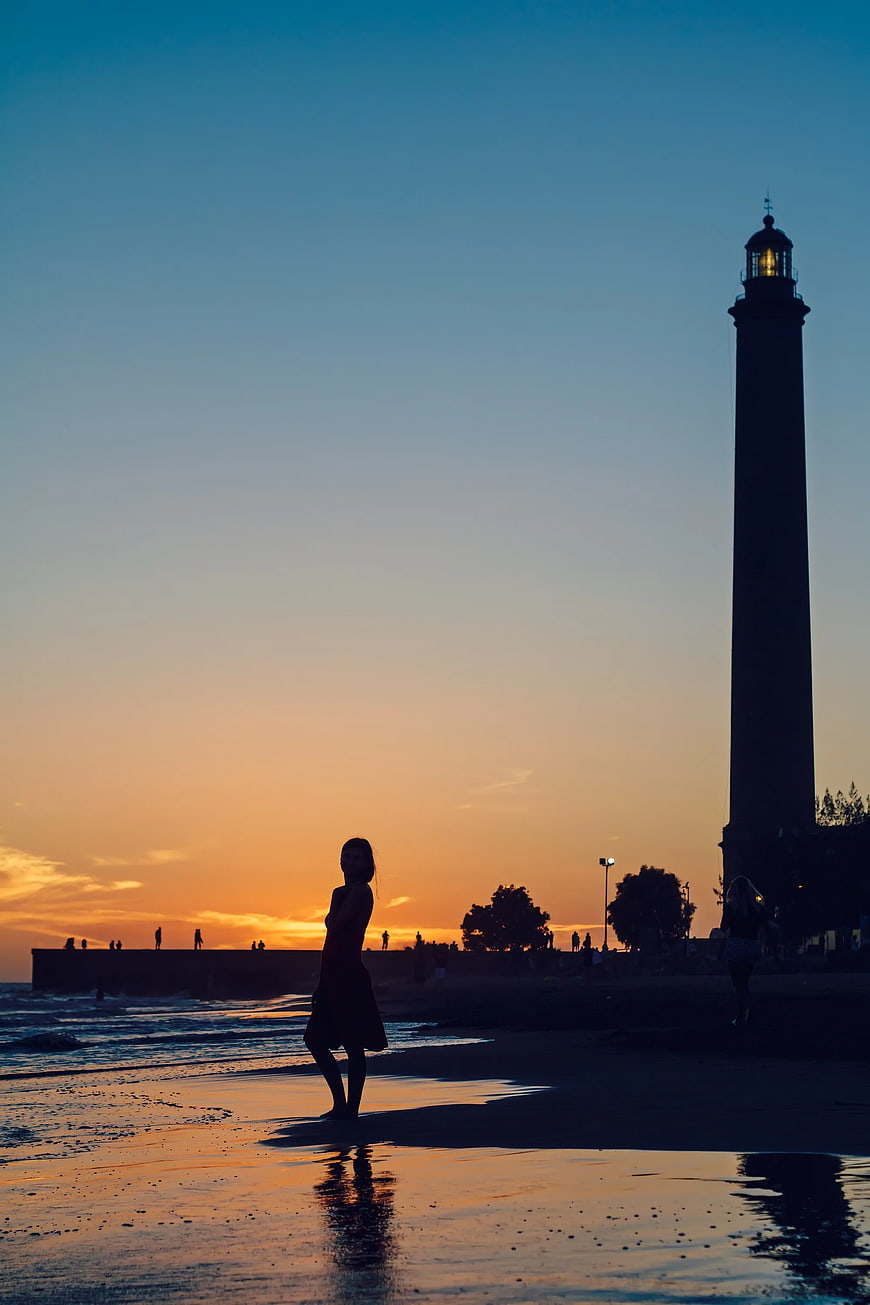 Woman Silhouette on Beach at Sunset with Lighthouse