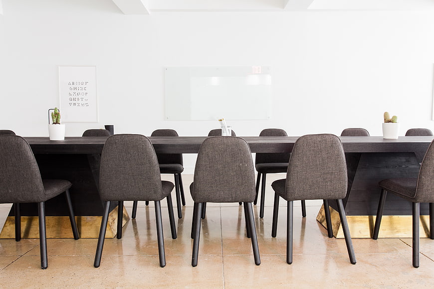 Modern minimalist conference room with long dark table and gray chairs