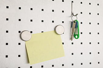 Yellow sticky note and keys on white pegboard