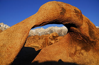 Natural Rock Arch Framing Snowy Mountain Peaks at Sunrise