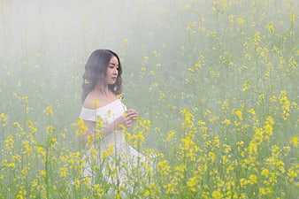 Woman in White Dress in Misty Yellow Flower Field