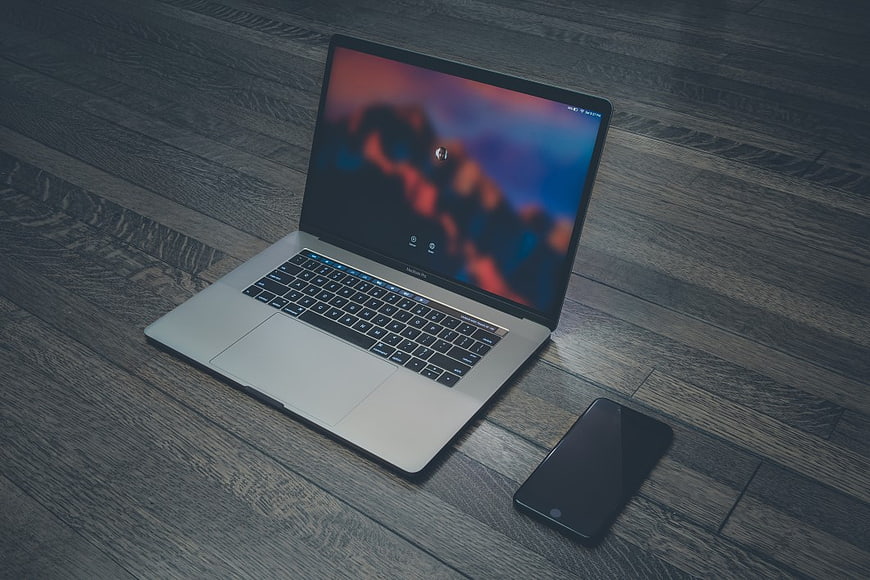 Silver Laptop and Smartphone on Dark Wood Floor