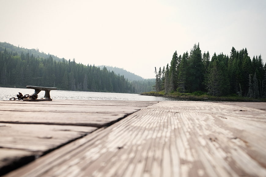 Low angle view of wooden dock planks leading to a serene lake