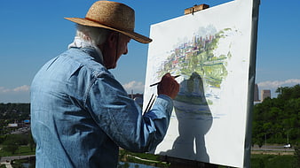 Senior man painting cityscape on canvas outdoors