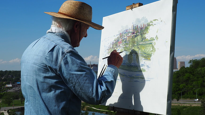 Senior man painting cityscape on canvas outdoors