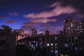 Dramatic purple twilight cityscape with illuminated apartment buildings