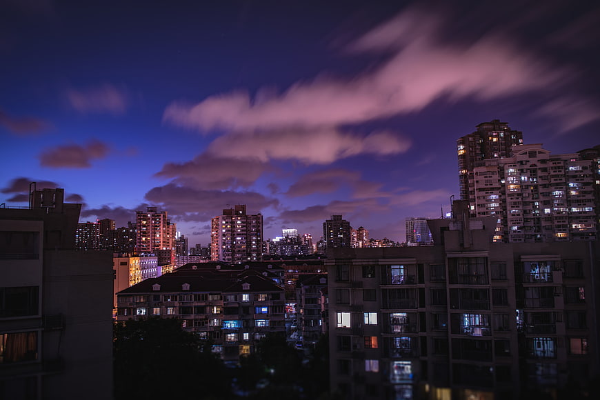 Dramatic purple twilight cityscape with illuminated apartment buildings