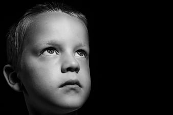Black and white portrait of a young boy looking up with a sad expression