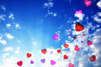 Colorful Heart Symbols Floating Against Blue Sky With White Clouds
