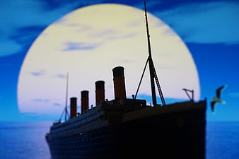 Silhouette of a vintage ocean liner with a seagull against a large moon