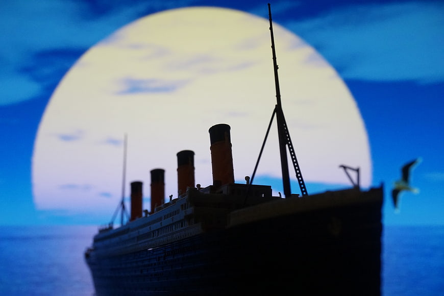 Silhouette of a vintage ocean liner with a seagull against a large moon
