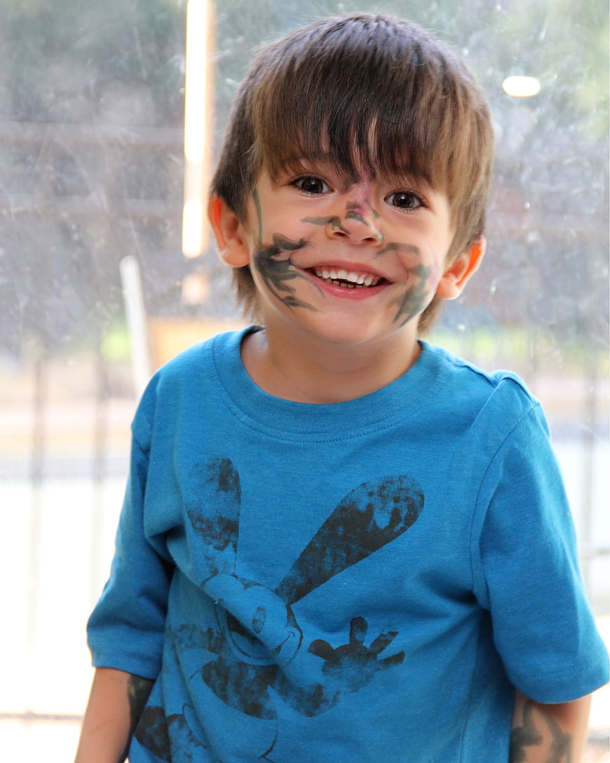 Smiling young boy with camouflage face paint and blue t-shirt